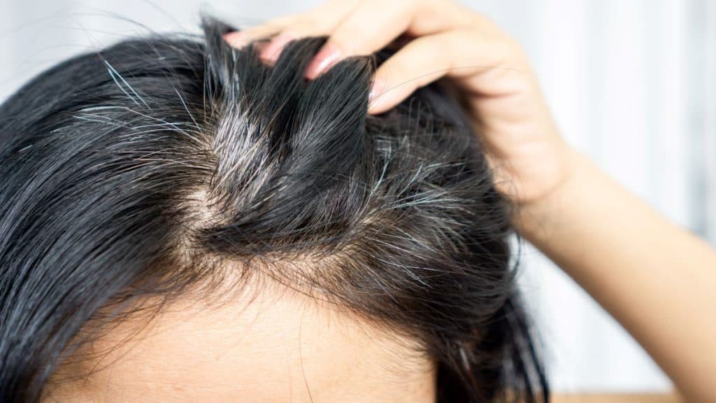 pessoa passando as mãos no cabelo com alguns fios brancos