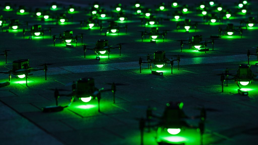Drones enfileirados no chão com luzes verdes acesas
