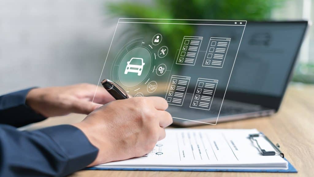 Conceito de garantia e seguro de serviço de carro, close up da mão de um agente de seguros verificando documentos para condições de seguro e usando o laptop para pesquisar informações no sistema enquanto trabalha em um escritório