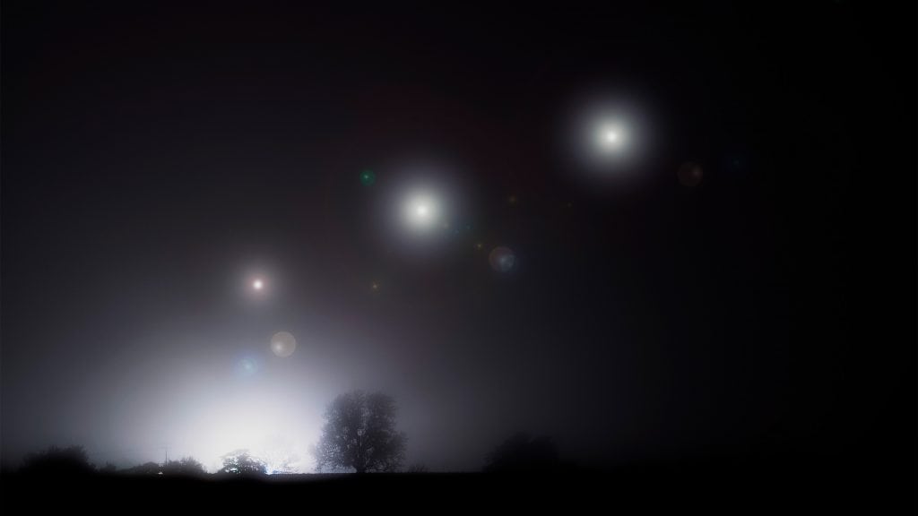 Luzes de óvnis em céu noturno com neblina em área rural