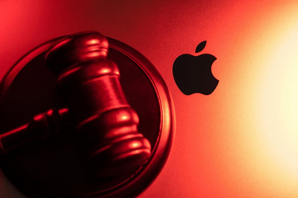 Martelo de juiz em cima de um MacBook; em destaque, o logo da Apple