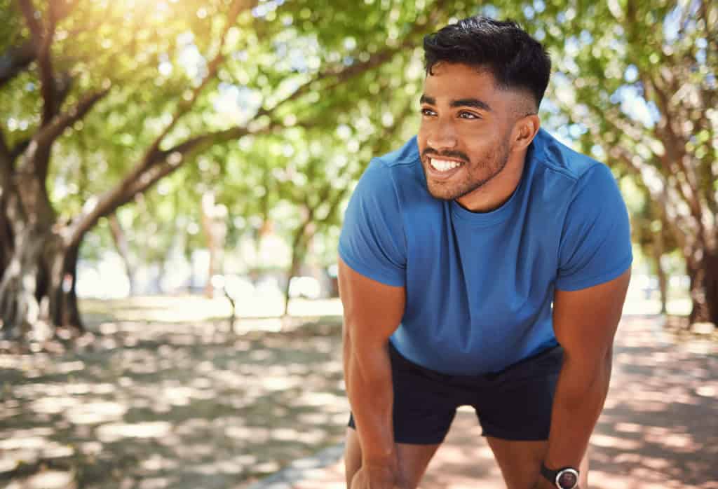 Homem jovem e saudável pratica corrida em parque